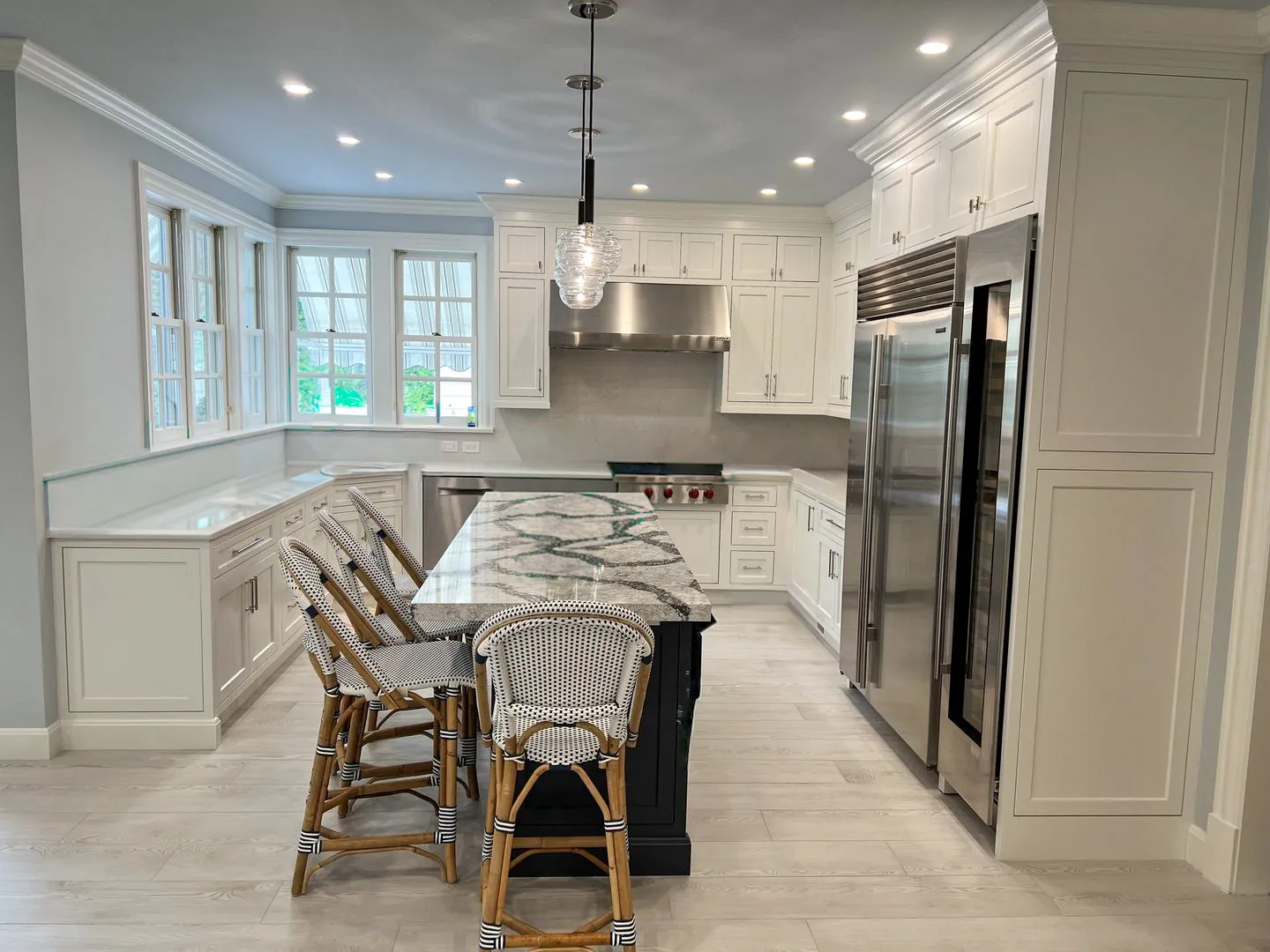 Remodelled kitchen with white shaker cabinetry, a navy island and marble counters