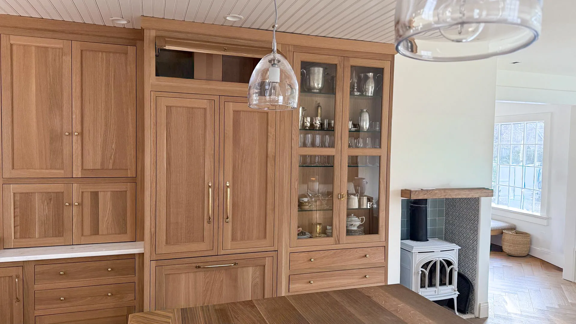 White oak built-ins with brass hardware and glass-front upper cabinets
