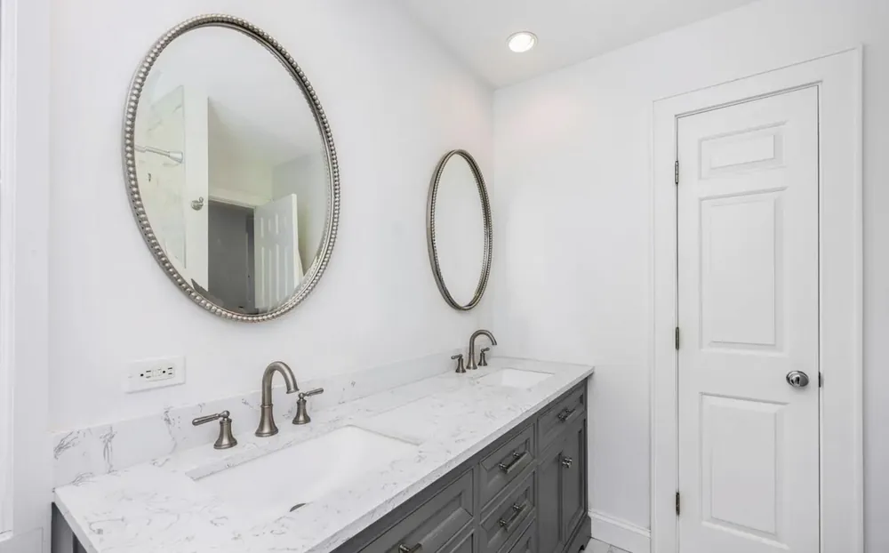 Primary bathroom with a double quartz vanity and round mirrors