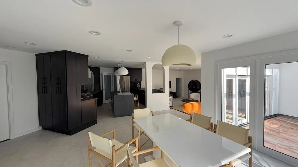 Open-plan kitchen and dining room with dark cabinetry and an arched opening