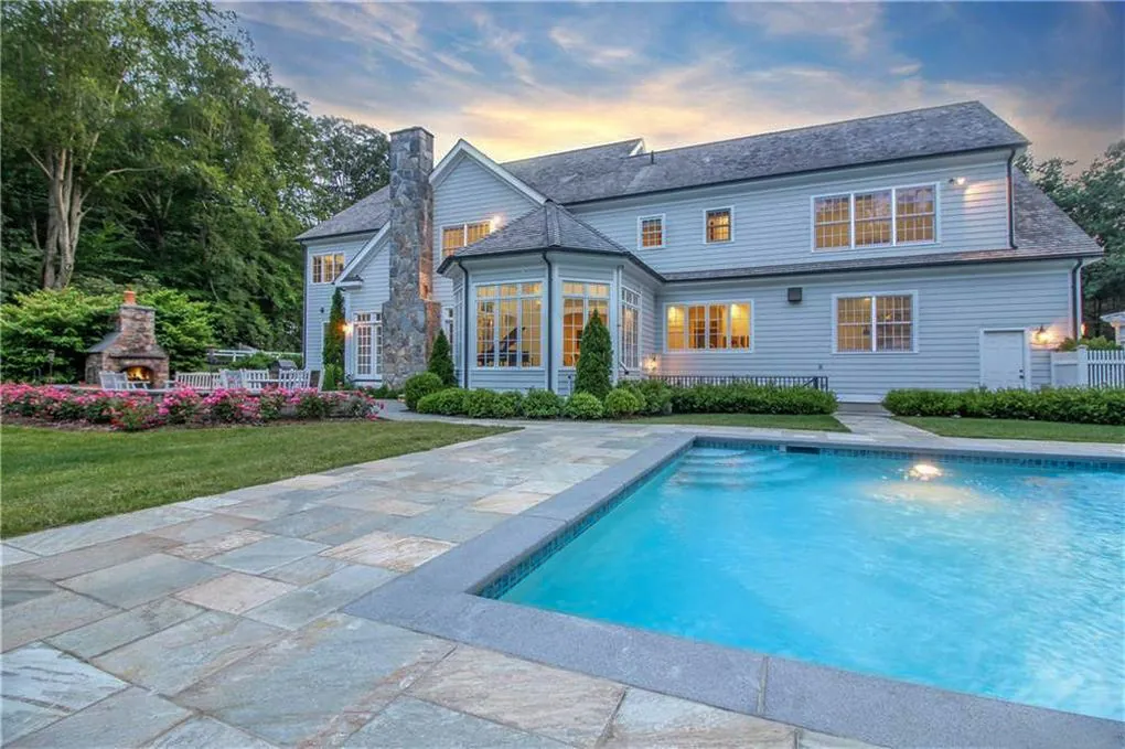 Bluestone pool terrace at dusk with an outdoor stone fireplace