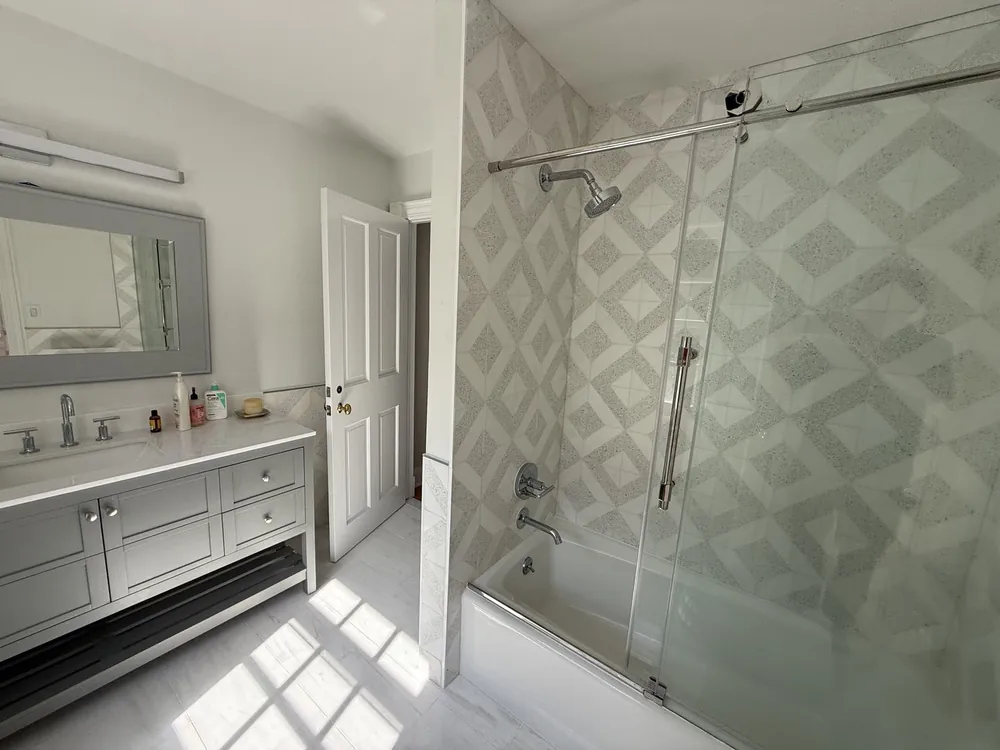 Primary suite bathroom with a double vanity and a patterned tile shower