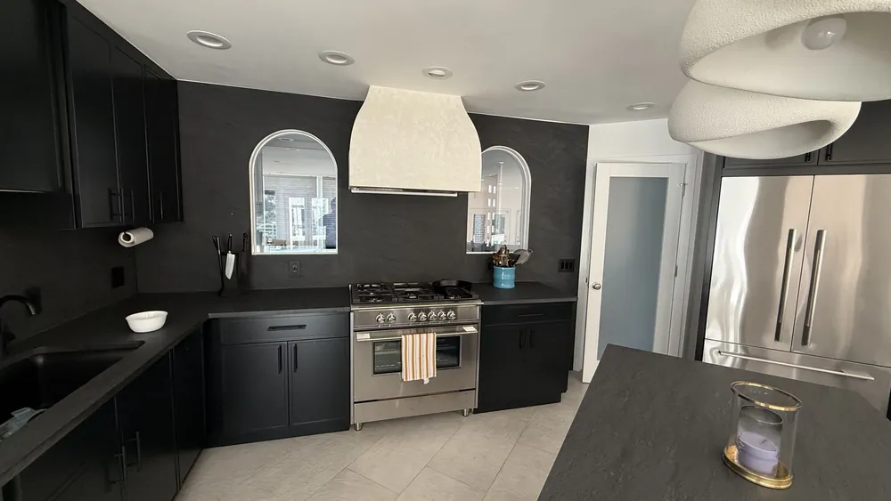 Open-plan kitchen with dark cabinetry, a plaster hood and arched openings