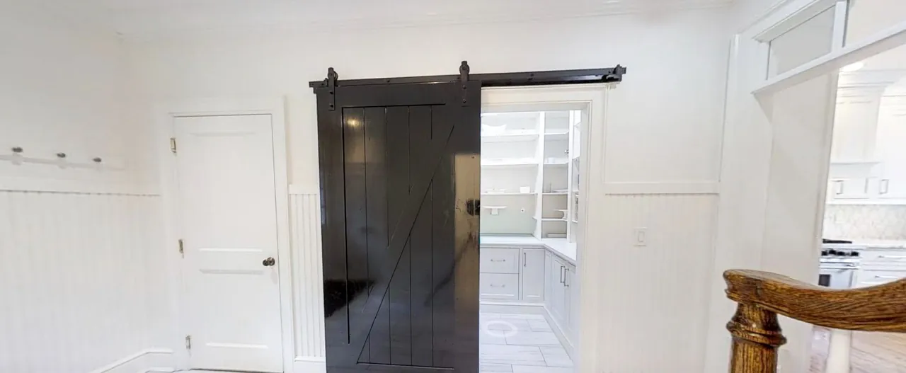 Black barn door sliding open to a butler's pantry