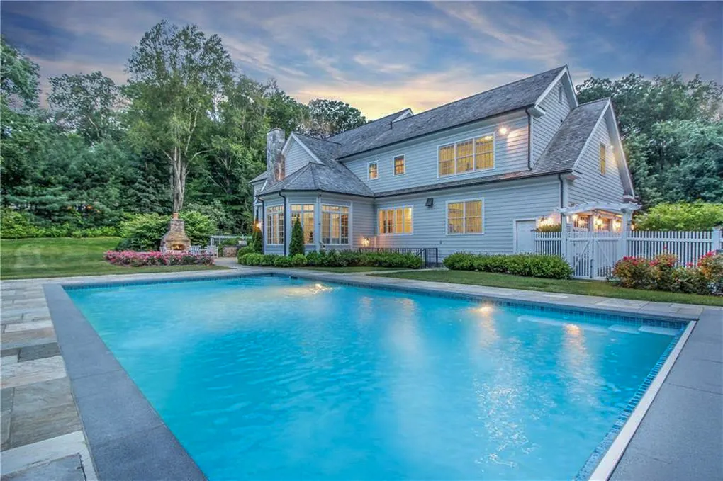 Pool and bluestone terrace at dusk behind a shingled house