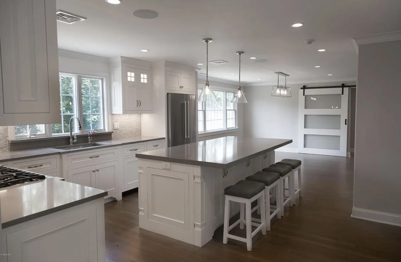 Kitchen with a long island, bar seating and a barn door to the pantry