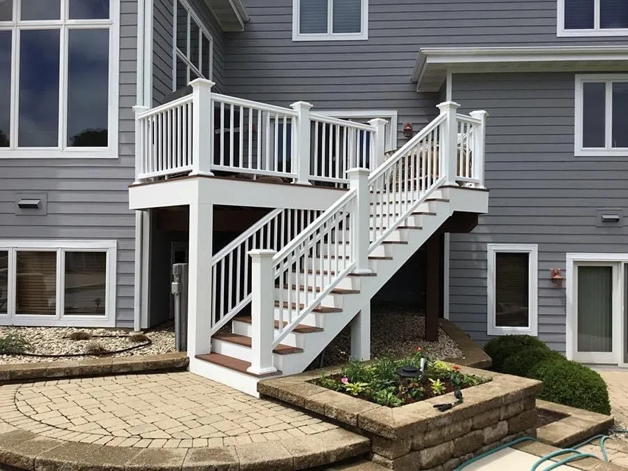 Raised deck and stair addition on the back of a grey clapboard house