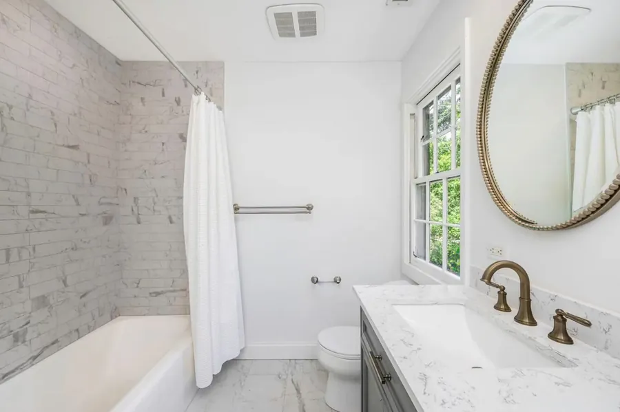 Bathroom with a marble tile surround, soaking tub and quartz vanity